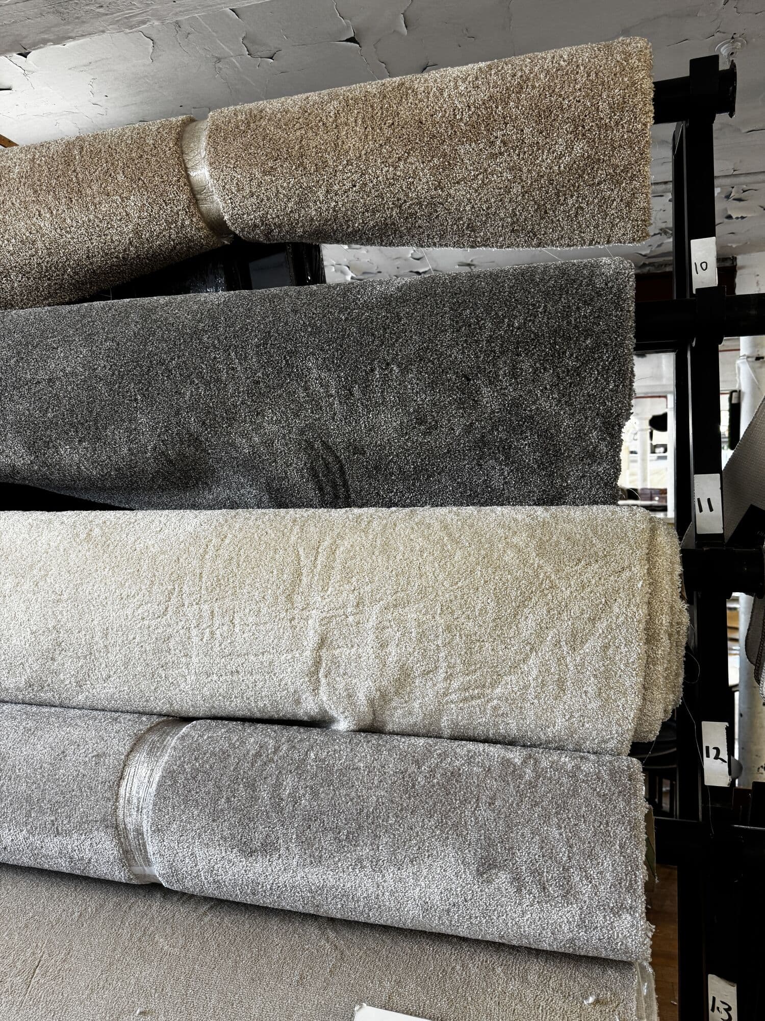 Stacked rolls of soft plush carpet in beige, grey and cream
